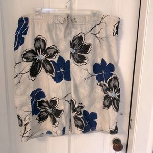 Men’s bathing suit trunks in white w/blue & black flower print.   Grey netting.